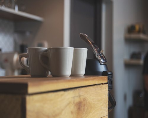 A close-up of a digital tablet on a wooden desk next to a ceramic mug in a local coffee shop