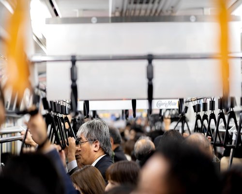 A busy urban environment with commuters on public transit using smartphones responsibly